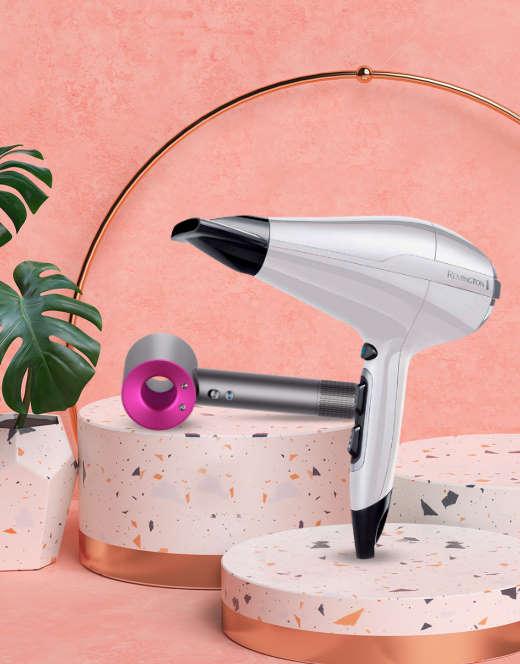 Modern hair dryers displayed on terrazzo stands with a pink background and gold arch.